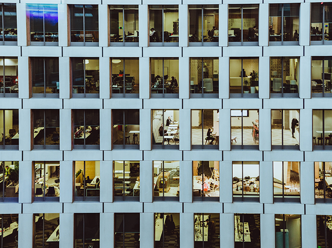 An image of outside an office building showing workers through the windows