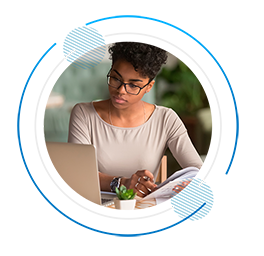 black woman looking at laptop and taking notes