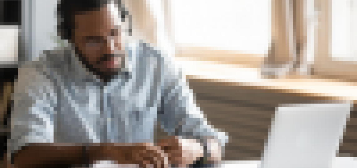 black man taking notes in front of a laptop